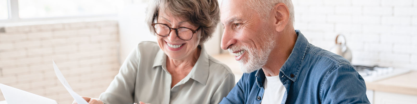 A senior man and senior woman sitting at a table looking at a document